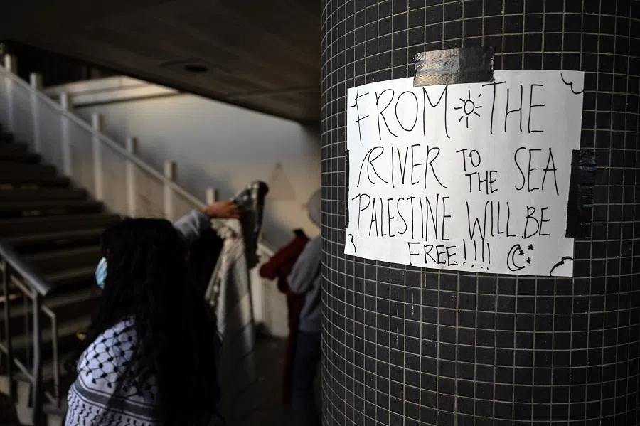  Pro-palestinian protesters wait under a poster reading “From the River to the Sea Palestine Will Be Free” taped on a column of the Los Angeles Police Department Van Nuys Station for the release of around 43 protesters who were arrested in the morning at the University of California Los Angeles in Los Angeles, California, on 6 May 2024. (Etienne Laurent/AFP)