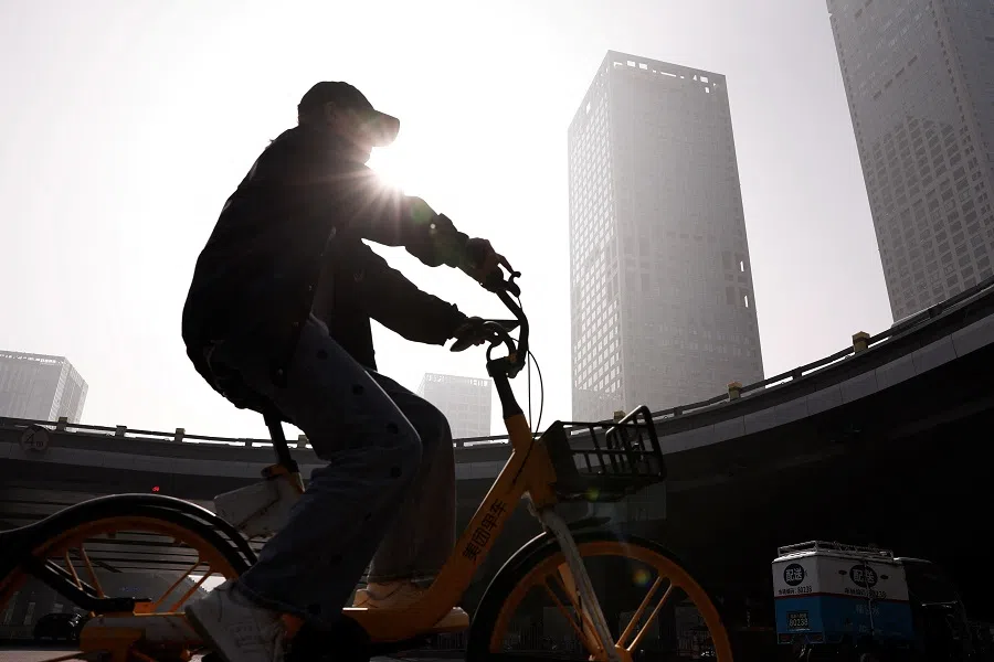 A person rides a bike past Beijing's central business district, in China, on 1 November 2023. (Tingshu Wang/Reuters)