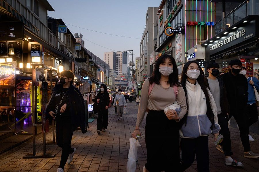 Pedestrians wearing face masks make their way along a street in Seoul on 16 November 2020. (Ed Jones/AFP)