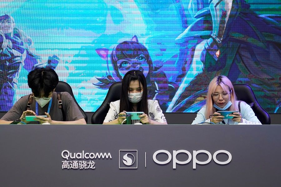 People play mobile games at a booth promoting Qualcomm and Oppo at the China Digital Entertainment Expo and Conference, also known as ChinaJoy, in Shanghai, China, 30 July 2021. (Aly Song/Reuters)