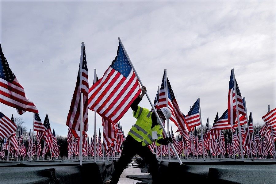 A worker plants an American flag along the National Mall in Washington, DC, US, on 18 January 2021. (Stefani Reynolds/Bloomberg)