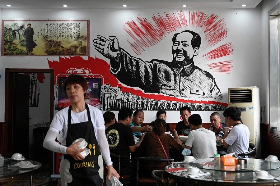 This photo taken on 26 May 2021 shows people eating in front of an image of late Chinese communist leader Mao Zedong at a restaurant in Shaoshan, Hunan province, China. (Jade Gao/AFP)
