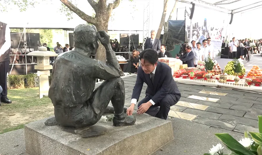 Taiwan President Lai Ching-te crouches down before Yoichi Hatta’s bronze statue.