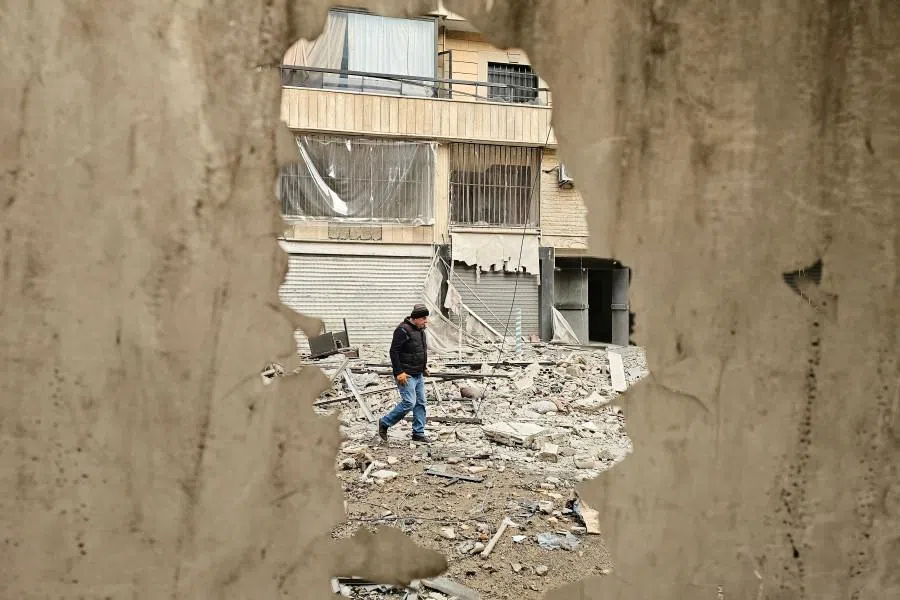 A man walks along a street strewn with building debris at the site of an overnight Israeli airstrike that targeted a neighbourhood in Beirut’s southern suburbs on 25 March 2026. (AFP)
