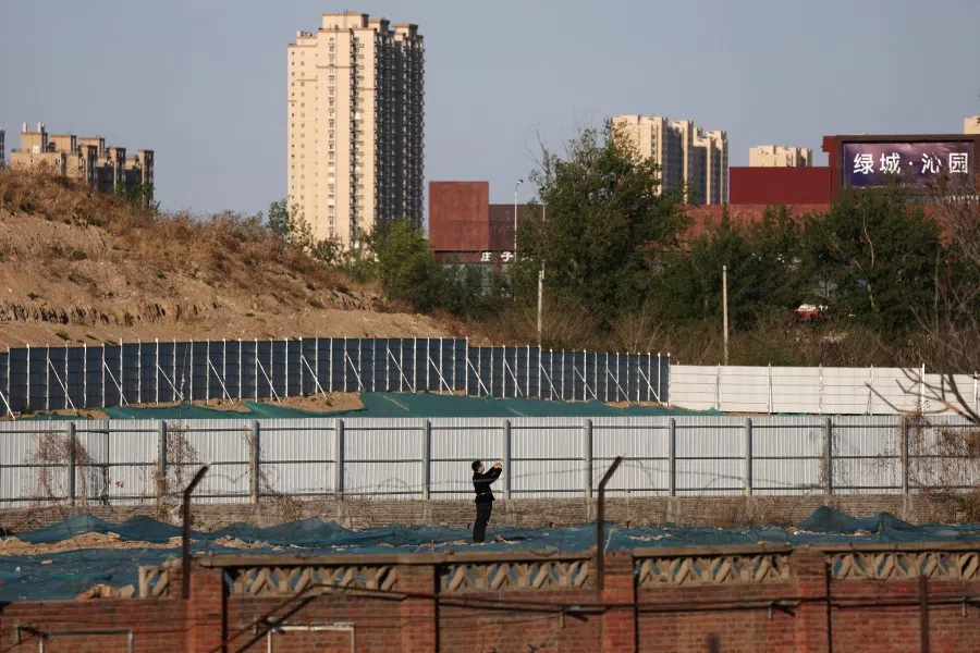 A man walks at a construction site near residential buildings in Beijing, China, 14 April 2022. (Tingshu Wang/Reuters)