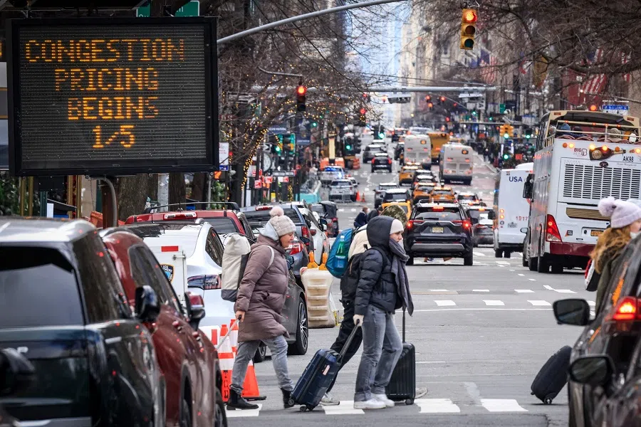 Pedestrians walk past a congestion pricing warning sign on 5th Avenue in New York City on 5 January 2024. (Kena Betancur/AFP)