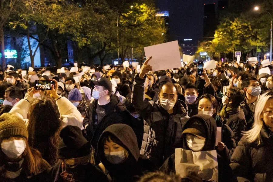 People hold white sheets of paper in protest of Covdi-19 restrictions, after a vigil for the victims of a fire in Urumqi, as outbreaks of the coronavirus disease continue in Beijing, China, 27 November 2022. (Thomas Peter/Reuters)
