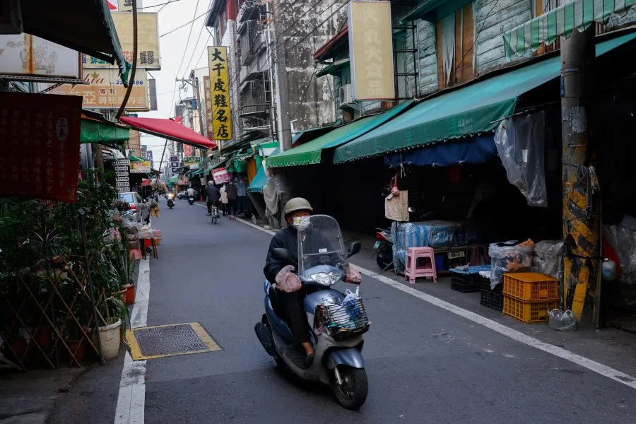 People ride on motor bikes in a morning market in Chiayi, Taiwan, 31 March 2023. (Ann Wang/Reuters)