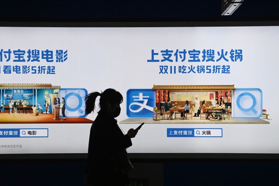 This file photo taken on 27 October 2020 shows a woman walking past an Alipay advertising billboard in a subway in Beijing. (Greg Baker/AFP)