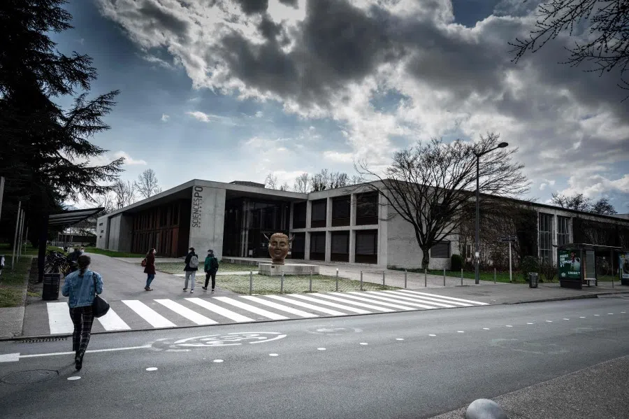 Students walk past the statue "Hypnos" by Spanish artist Jose Seguiri by the entrance of the Sciences-Po Grenoble's campus, in Saint-Martin-d'Heres, near Grenoble, south eastern France, on 8 March 2021. (Jean-Philippe Ksiazek/AFP)
