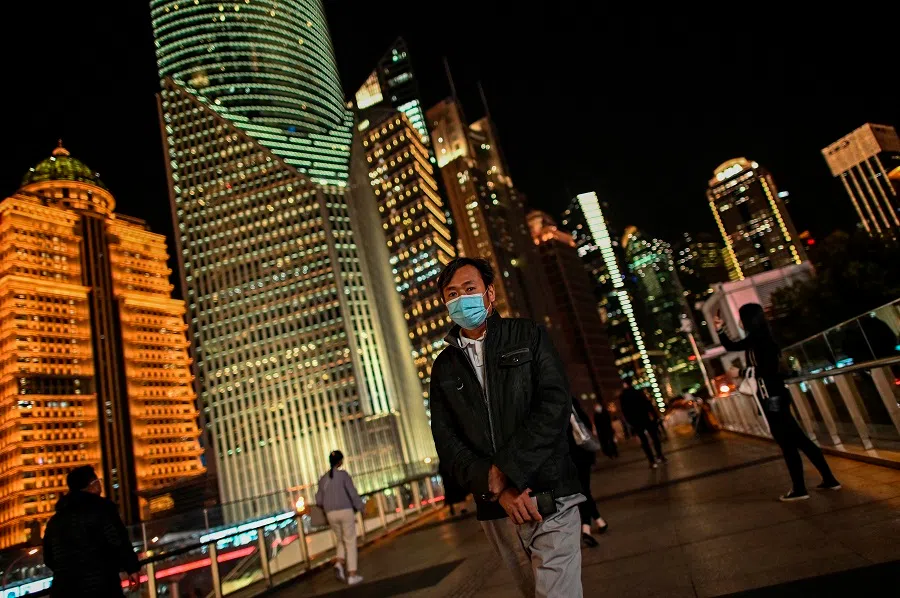 A man walks over a bridge in the financial district of Lujiazui in Shanghai on 9 November 2020 (Hector Retamal/AFP)