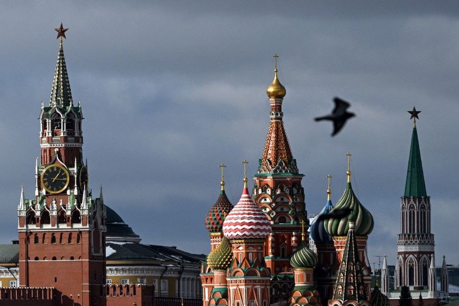 A pigeon flies in front of the Kremlin's Spasskaya tower (left) and Saint Basil's cathedral (centre) in Moscow on 1 March 2023. (Kirill Kudryavtsev/AFP)