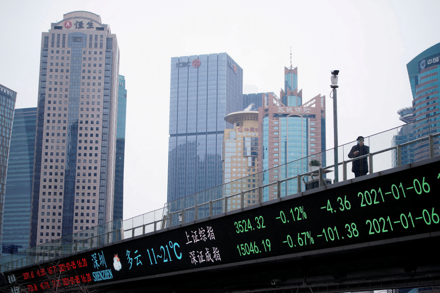 A man stands on an overpass with an electronic board showing Shanghai and Shenzhen stock indexes, at the Lujiazui financial district in Shanghai, China, 6 January 2021. (Reuters/Aly Song/File Photo)