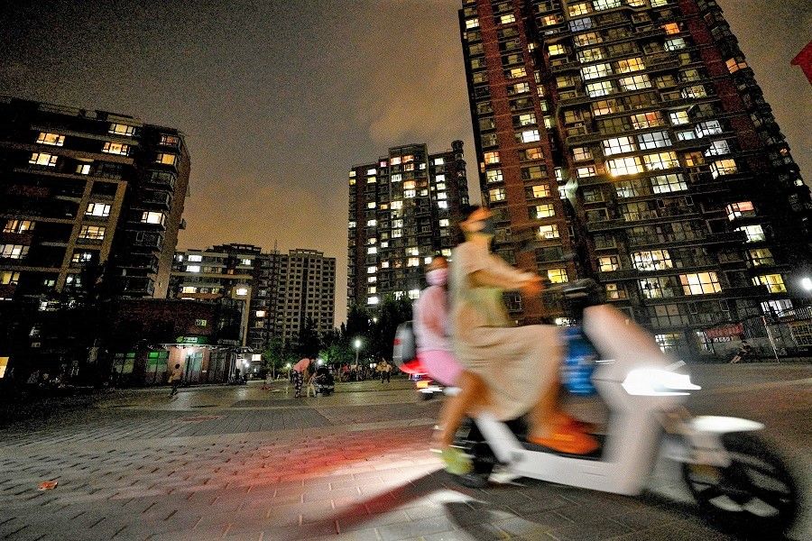 This photo taken on 17 August 2022 shows a woman ferrying a child in a vehicle through a residential complex in Shangdi neighbourhood, Beijing, China. (Noel Celis/AFP)