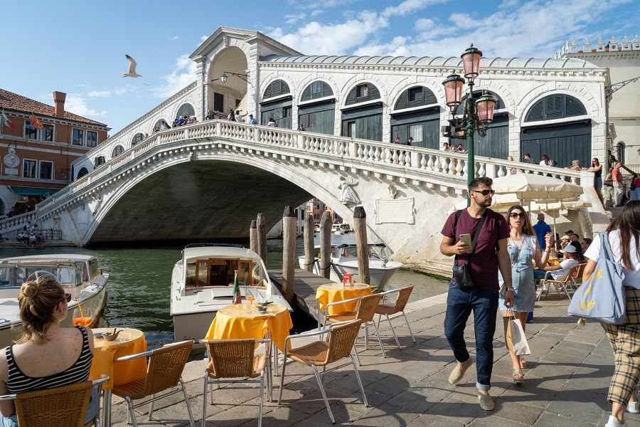 Tourists pass a cafe terrace at the Rialto Bridge in Venice, Italy on 5 June 2021. (Giulia Marchi/Bloomberg)