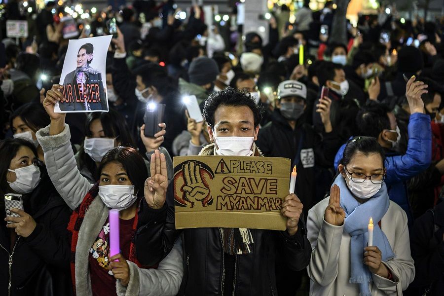 Myanmar activists hold up the three-finger salute and a picture of detained Myanmar civilian leader Aung San Suu Kyi during a protest in Tokyo on 6 February 2021, condemning the military coup in Myanmar. (Charly Triballeau/AFP)