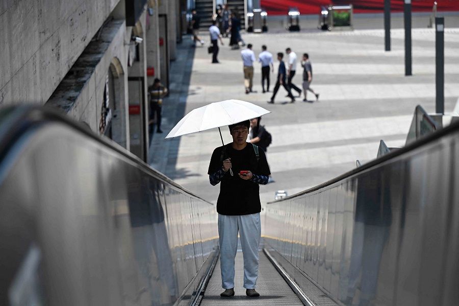 A man uses an umbrella to shelter from the sun in Guangzhou, Guangdong province, China, on 2 June 2023. (AFP)
