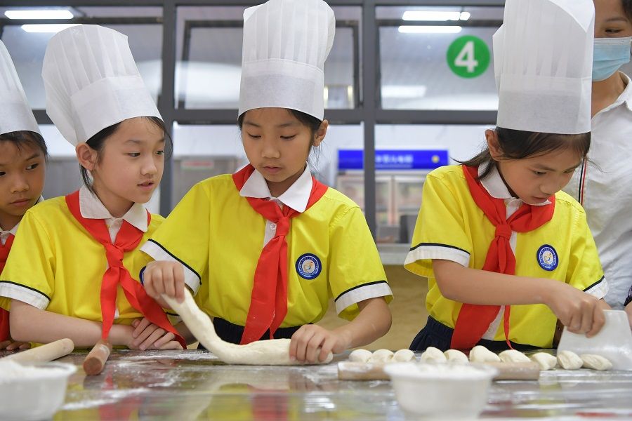 Primary school students work with flour during a cooking lesson in school, in Ganzhou, Jiangxi province, China, on 13 May 2022. (Xinhua)