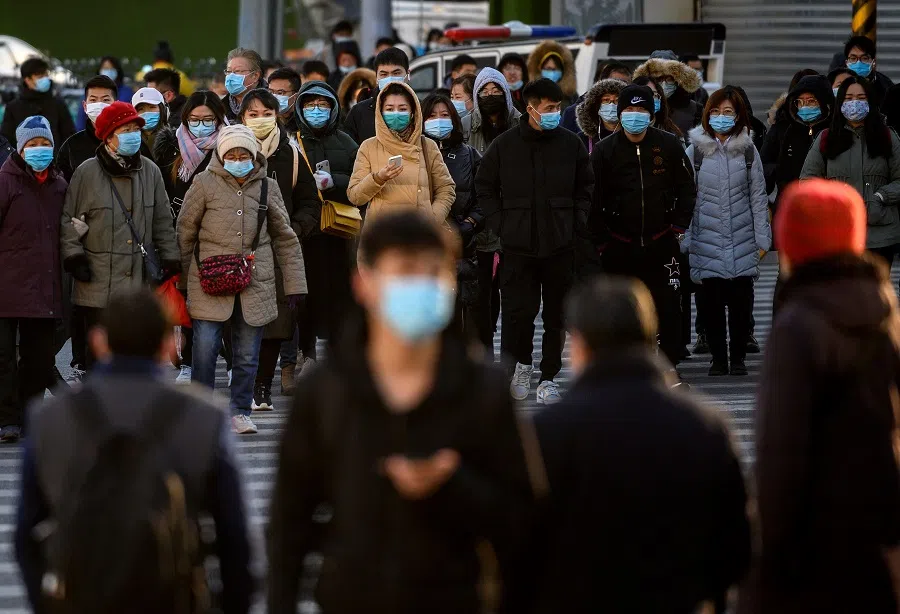 People wearing face masks walk along a street during a rush hour in Bejing on 16 December 2020. (Noel Celis/AFP)