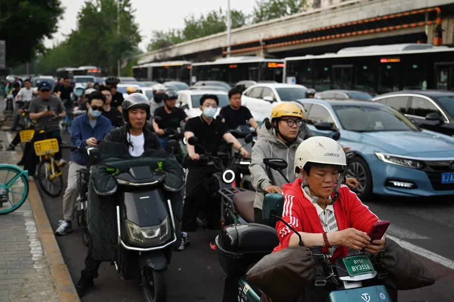 People wait in a cycle lane at the end of the work day in Beijing, China on 21 May 2025. (Greg Baker/AFP)