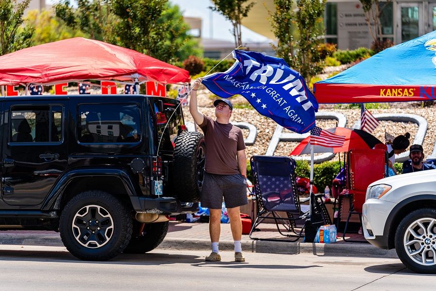 A person adjusts a campaign flag displayed on a vehicle outside of the BOK Center ahead of a rally for US President Donald Trump in Tulsa, Oklahoma, US, on 17 June 2020. (Christopher Creese/Bloomberg)