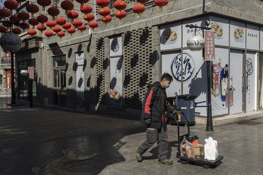 A courier pushes a cart down a quiet shopping street in the Qianmen area of Beijing, China, on 17 March 2020. (Qilai Shen/Bloomberg)