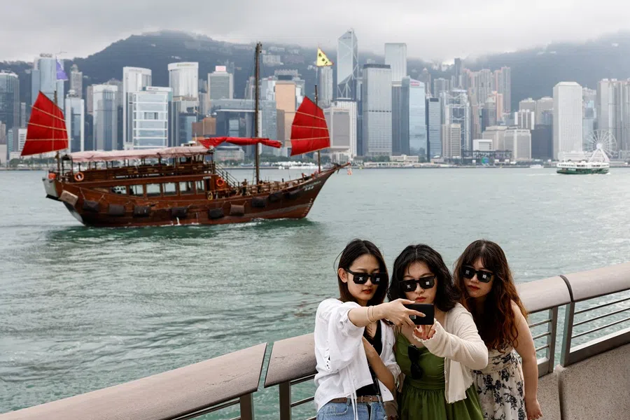 Tourists take photos in front of Victoria Harbour, in Tsim Sha Tsui, in Hong Kong, China, on 29 April 2024. (Tyrone Siu/Reuters)