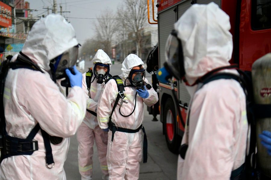 This photo taken on 15 January 2021 shows people in protective suits preparing to spray disinfectant on a street at Gaocheng district, which was declared a high-risk area for Covid-19 in Shijiazhuang, in China's Hebei province. (STR/CNS/AFP)