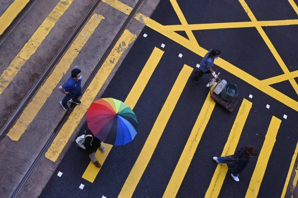 People cross a pedestrian crossing in Hong Kong on 16 May 2022. (Peter Parks/AFP)