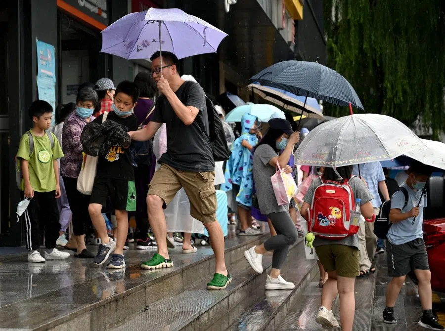 This picture taken on 29 July 2021, shows students and parents walking after attending a private after-school education in Haidan district of Beijing. (Noel Celis/AFP)