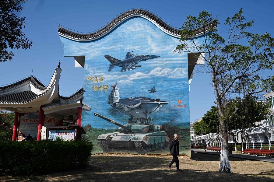 A man walks past a military-themed mural at a public park on Pingtan Island in China's southeast Fujian province on 14 January 2024. The slogan at left reads "China Dream; Strong-Army Dream". (Greg Baker/AFP)