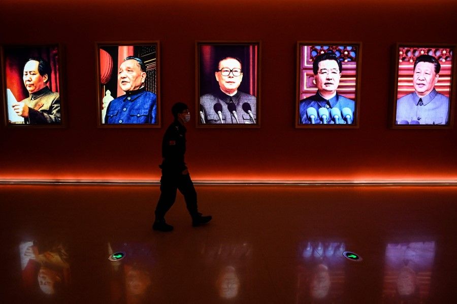 This file photo taken on 15 October 2022 shows a man walking past portraits of (left to right) late Chinese chairman Mao Zedong and former Chinese leaders Deng Xiaoping, Jiang Zemin, Hu Jintao and current president Xi Jinping at Yan'an Revolutionary Memorial Hall in Yan'an city, China's northwest Shaanxi province. Wang Huning has served under Jiang, Hu and Xi. (Jade Gao/AFP)