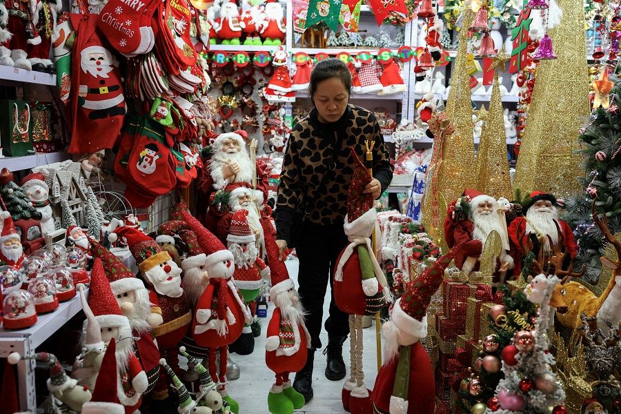 A vendor sorts products at a booth selling Christmas decorations at a mall in Beijing, China, on 14 December 2023. (Tingshu Wang/Reuters)