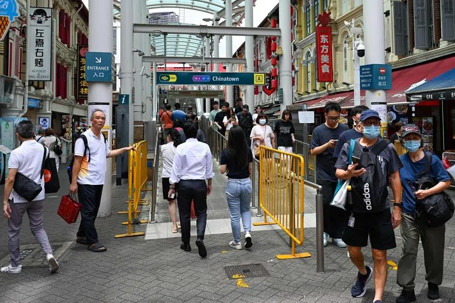 People walk along the street next to the Chinatown MRT station in the Chinatown district of Singapore on 12 February 2026. (Roslan Rahman/AFP)