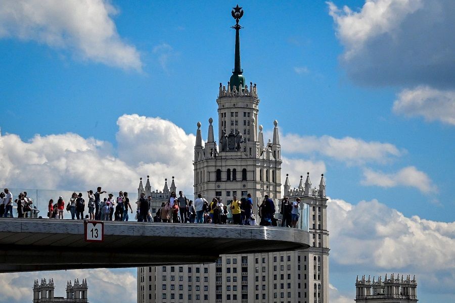 People walk on an overhung pedestrian bridge near a Stalin-era skyscraper, in central Moscow, Russia on 16 May 2021. (Yuri Kadobnov/AFP)