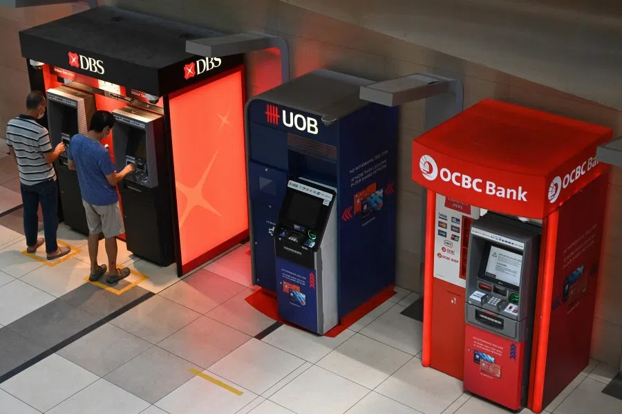 People use the automated teller machines at a terminal of the Changi International Airport in Singapore on 7 December 2020. (Roslan Rahman/AFP)