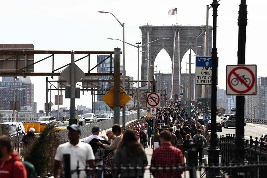 Tourists and pedestrians walk across the Brooklyn Bridge in New York on 30 March 2026. (Charly Triballeau/AFP)