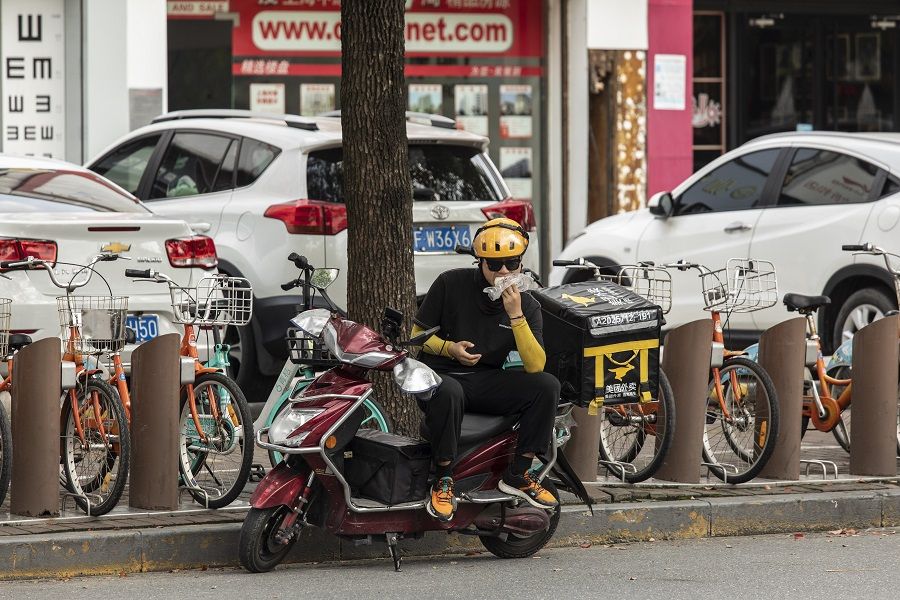 A delivery driver for Meituan takes a quick bite while sitting on his scooter in Shanghai, China on 30 August 2021. (Qilai Shen/Bloomberg)