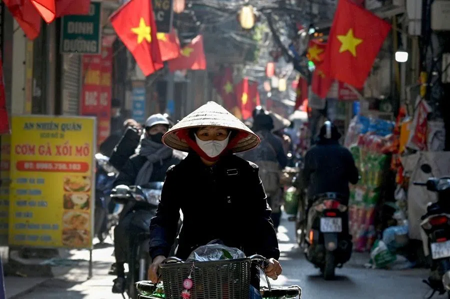 A street vendor rides a bicycle along a street under Vietnamese flags in Hanoi on 8 January 2026. (Nhuc Nguyen/AFP)
