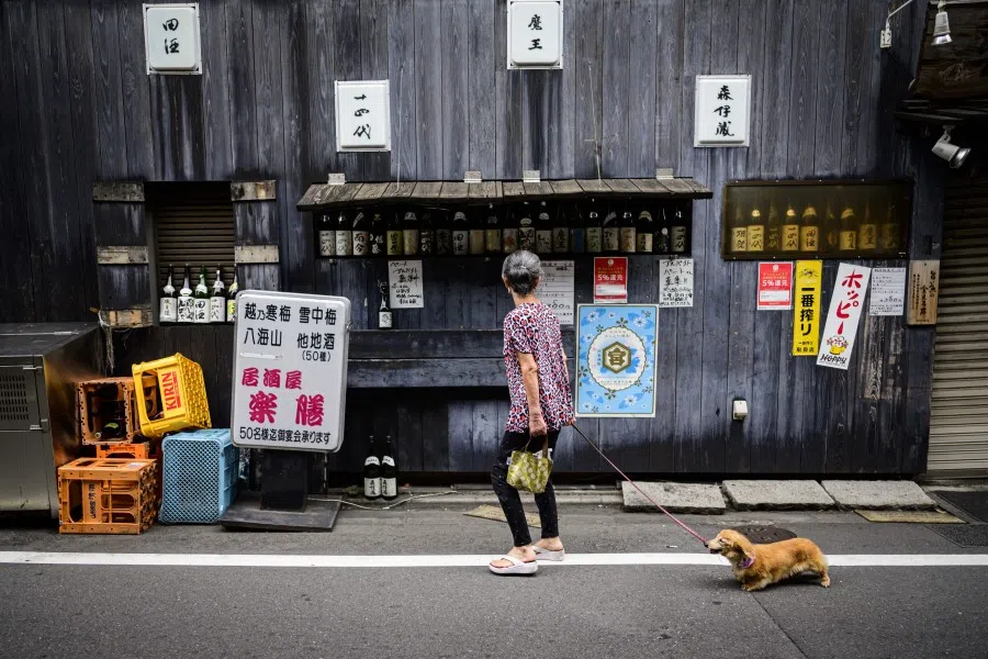 An elderly woman walks her dog in the Nakameguro neighbourhood of Tokyo on 18 June 2020. (Behrouz Mehri/AFP)
