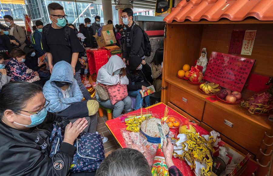 People sit around a stall waiting for a "villain hitting" ceremony in Hong Kong, China. (iStock)