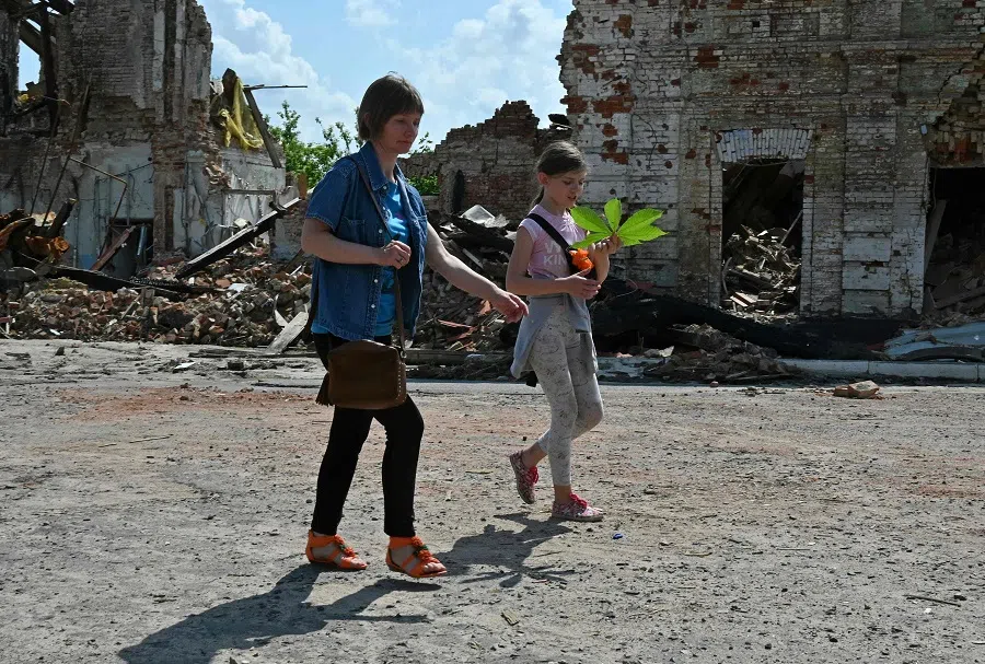 Local residents walk past a building destroyed by shelling in the centre of Kupiansk, Kharkiv region, Ukraine, on 26 May 2023, amid the Russian invasion of Ukraine. (Sergey Bobok/AFP)