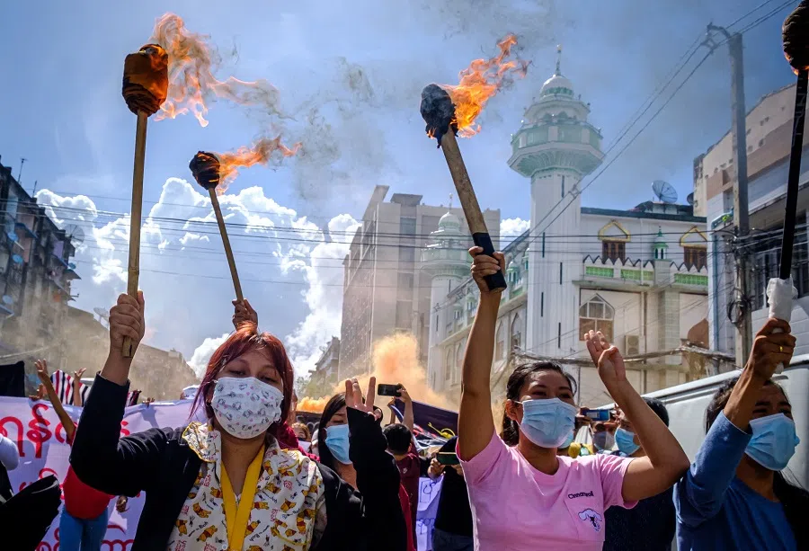 Women carry burning torches as they march during a demonstration against the military coup in Yangon, Myanmar, on 14 July 2021. (STR/AFP)