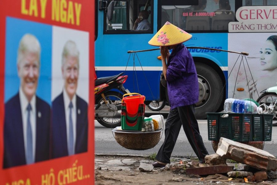 A street vendor walks past a billboard for a photo studio featuring an image of US President Donald Trump in Hanoi, 24 November 2020. (Nhac Nguyen/AFP)