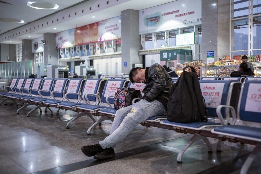 A man sleeps as he waits for a train at Kunshan Railway Station, 17 January 2020. The movement of people during the Chinese New Year period is usually the greatest human migration of the year. (Qilai Shen/Bloomberg)