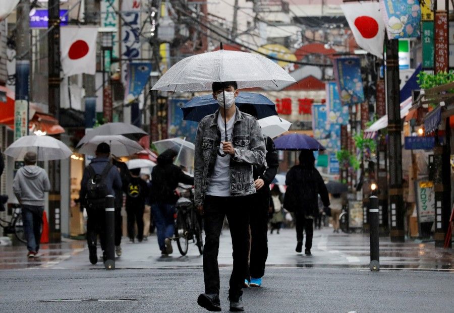 A man wearing a protective face mask, amid the coronavirus disease (COVID-19) pandemic, makes his way at a local shopping street in Tokyo, Japan, 5 May 2021. (Kim Kyung-Hoon/Reuters)