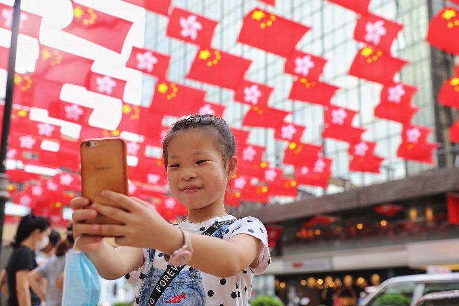 A girl takes a photograph beneath the flags of Hong Kong and mainland China, in Hong Kong, in this file photo. (CNS)