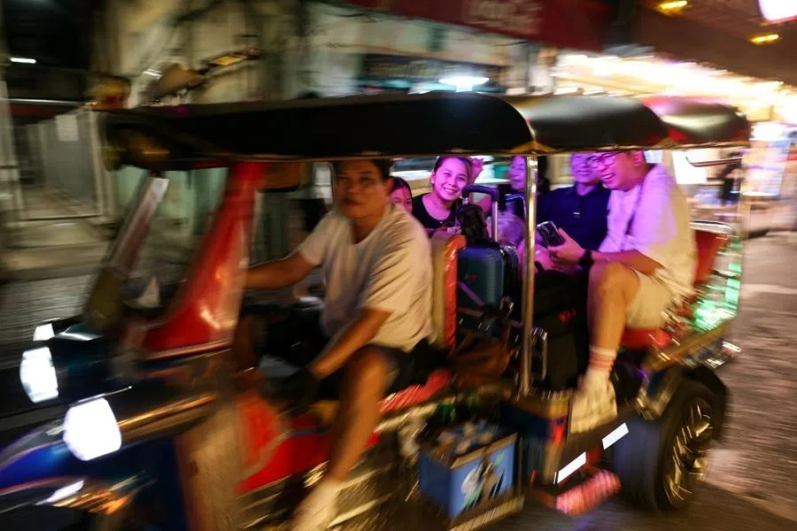 Commuters smiling as they speed past in a Tuk Tuk, a motorised rickshaw, at Bangkok’s Chinatown in the Yaowarat district on 10 December 2025.