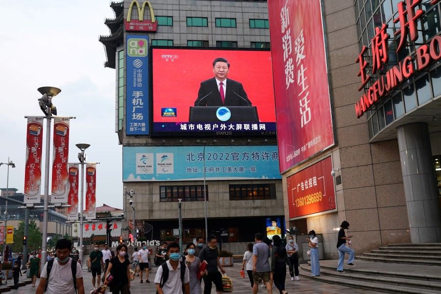 People walk past a giant screen broadcasting a news footage of Chinese President Xi Jinping, at a shopping area in Beijing, 31 July 2020. (Tingshu Wang/REUTERS)