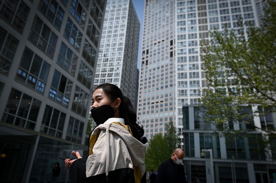 A woman wearing a face mask walks in the Central Business District in Beijing on 14 April 2020. (Wang Zhao/AFP)
